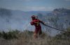 A firefighter directs water on a grass fire burning on an acreage behind a residential property in Kamloops, B.C., June 5, 2023. THE CANADIAN PRESS/Darryl Dyck