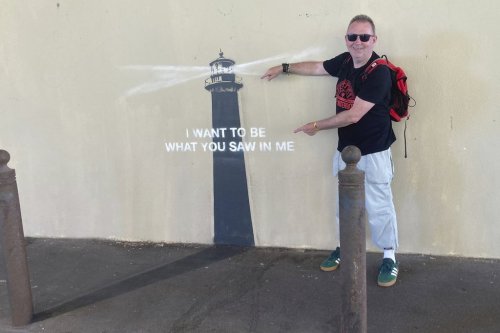 A man poses by an artwork by street artist Banksy, Friday, May 30, 2025 in Marseille, southern France. (AP Photo/Bishr Eltoni)