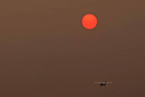 Tim Smith/The Brandon Sun
                                The sun, obscured by smoke from forest fires in northern Manitoba, glows pink in the sky as an aircraft takes flight at the Brandon Airport.