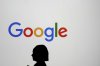 A woman walks by a giant screen with a logo at an event at the Paris Google Lab on the sidelines of the AI Action Summit in Paris on Sunday, Feb. 9, 2025. (AP Photo/Thibault Camus, File)