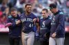 Seattle Mariners' Julio Rodriguez, second from left, is helped off the field after being struck by a batted ball hit by Randy Arozarena as manager Dan Wilson, right, walks with him during the third inning of a baseball game against the Los Angeles Angels, Saturday, June 7, 2025, in Anaheim, Calif. (AP Photo/Mark J. Terrill)