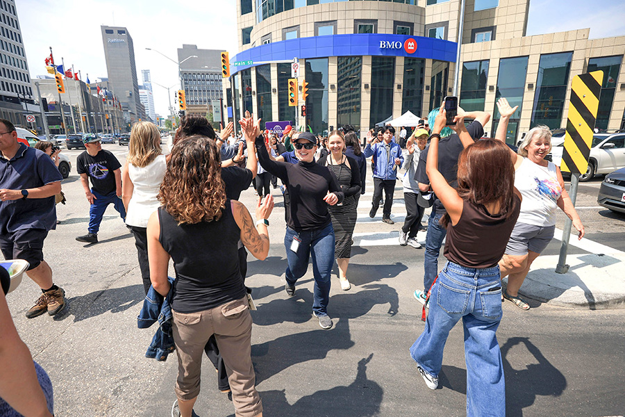 Photo of pedestrians and event goers as the high-five each other crossing Portage and Main over the lunch-hour Tuesday.