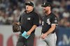 Umpire Dan Bellino holds the glove of Chicago White Sox pitcher Tyler Gilbert before he pitches during the fifth inning of a baseball game against the New York Yankees Thursday, Sept. 25, 2025, in New York. (AP Photo/Frank Franklin II)