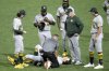 Athletics manager Mark Kotsay, second from right, watches as Zack Gelof, bottom, is tended to by a team trainer during the fifth inning of a baseball game against the Pittsburgh Pirates in Pittsburgh, Friday, Sept. 19, 2025. (AP Photo/Gene J. Puskar)