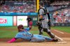 Philadelphia Phillies' Harrison Bader, left, slides safely into home on a ground out by Alec Bohm as Miami Marlins catcher Liam Hicks, right, looks on during the first inning of a baseball game, Thursday, Sept. 25, 2025, in Philadelphia. (AP Photo/Chris Szagola)