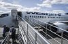 WestJet passengers deplane on the tarmac at Yellowknife Airport on Tuesday, July 22, 2025. THE CANADIAN PRESS/Jeff McIntosh