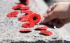 A person places a poppy on the Tomb of the Unknown Soldier following a ceremony commemorating the 25th anniversary of the entombment at the National War Memorial, Wednesday, May 28, 2025 in Ottawa.  THE CANADIAN PRESS/Adrian Wyld