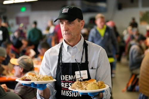 FILE - Volunteer Brent Cohen carries plates of food to guests during the annual Thanksgiving banquet at the Denver Rescue Mission on Nov. 22, 2023, in Denver. (AP Photo/David Zalubowski, File)