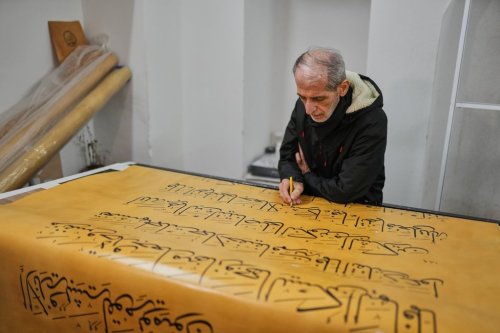 Iraqi calligrapher Ali Zaman works in a scroll of a massive handwritten manuscript of the Quran, Islam's holy book, at the Mihrimah sultan mosque, in Istanbul, Turkey, Wednesday, Jan. 14, 2026. (AP Photo/Francisco Seco)