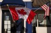 A worker at The Pier, one of three restaurants in town, readjusts Canadian and American flags hanging outside the business, Monday, March 17, 2025, in Point Roberts, Wash. (AP Photo/Lindsey Wasson, File)