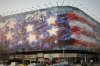 A billboard depicting a damaged U.S. aircraft carrier with disabled fighter jets on its deck and a sign reading in Farsi and English, 