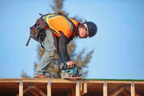 A construction worker at the Apollo Heights Phase 2 construction site does a little trimming with an electric saw while working at the top of one of the structures on site on a sunny and warm Thursday afternoon. The site, owned by Keller Developments, is part of a $47-million project that will add 165 rental units to Brandon’s housing stock. (Matt Goerzen/The Brandon Sun)