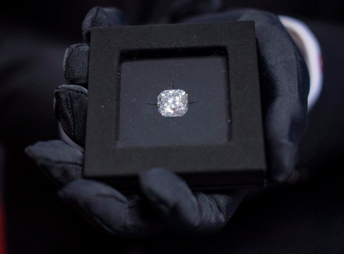 An employee of De Beers Canada holds a 12.8 carrot diamond worth $1 million at the opening of their facility in Calgary Wednesday, July 6, 2016. THE CANADIAN PRESS/Jeff McIntosh