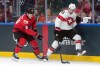 Canadian forward Nathan MacKinnon (29) and Swiss counterpart Nico Hischier (13) battle for the puck at the Winter Olympics in Milan on Friday, Feb. 13, 2026. THE CANADIAN PRESS/Darryl Dyck