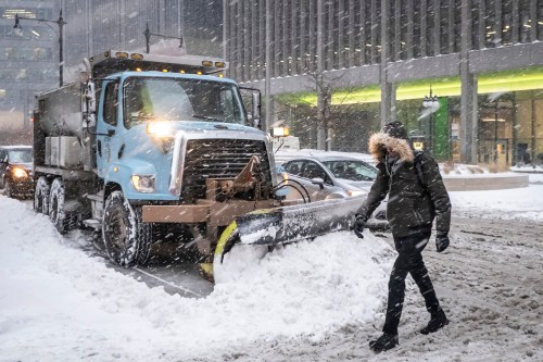 FILE - A man crosses Wacker Drive in front of a waiting city snowplow in Chicago, Jan. 28, 2019. (Rich Hein/Chicago Sun-Times via AP, File)